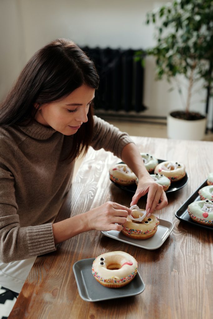 young woman decorating iced doughnuts