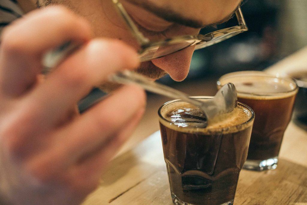 bespectacled man smelling a glass of coffee