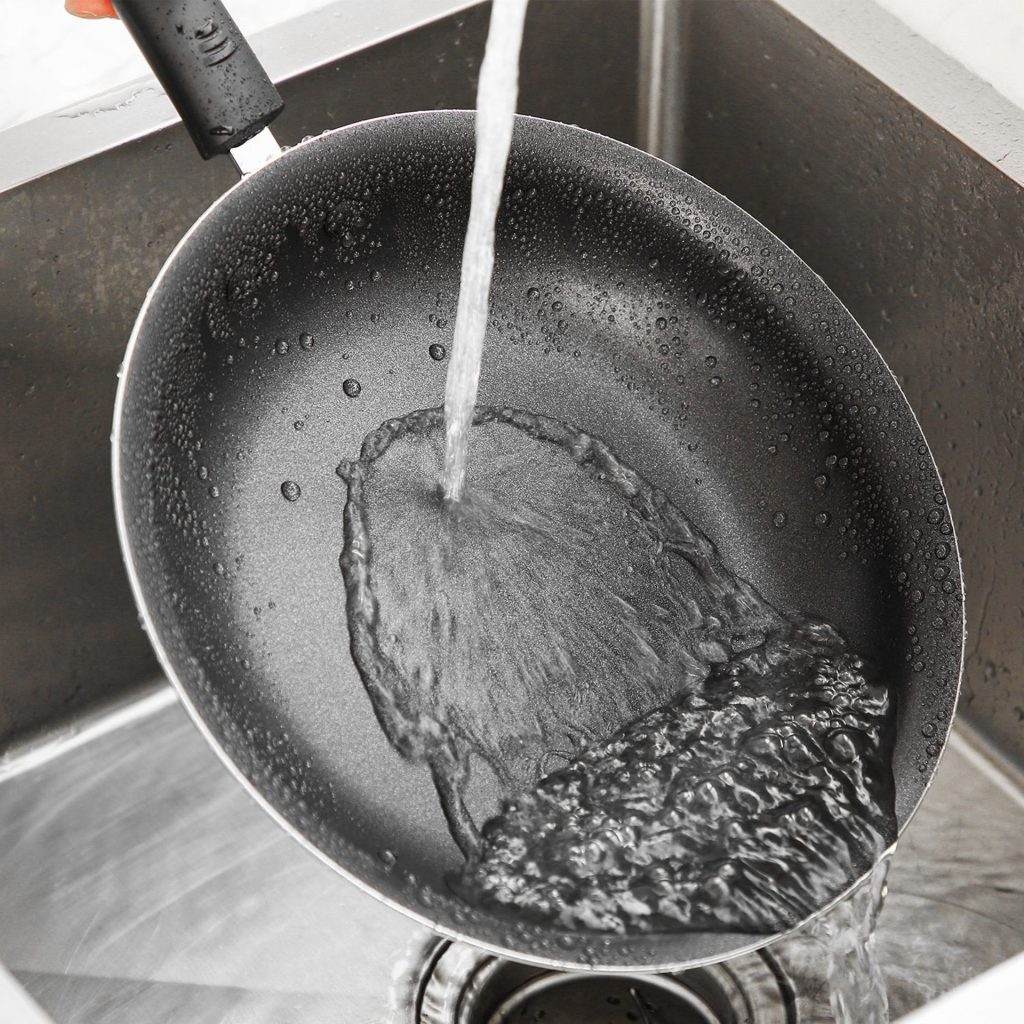 cleaning a frying pan with running water from the tap