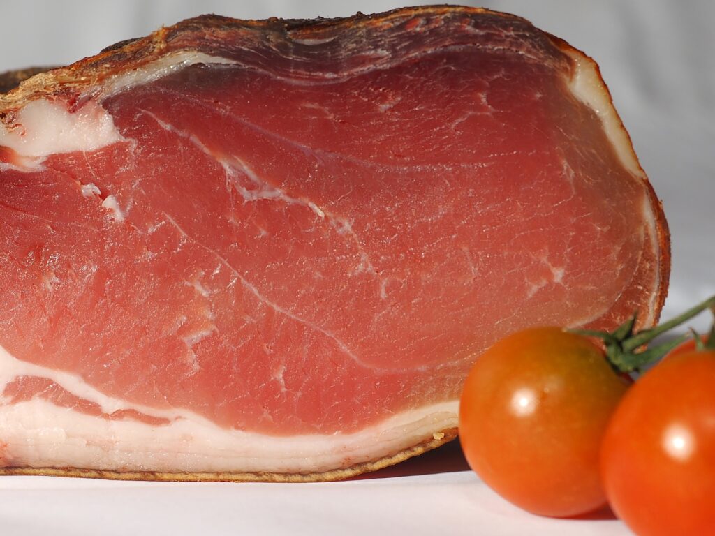 Uncooked Gammon with 2 ripe tomatoes on the right