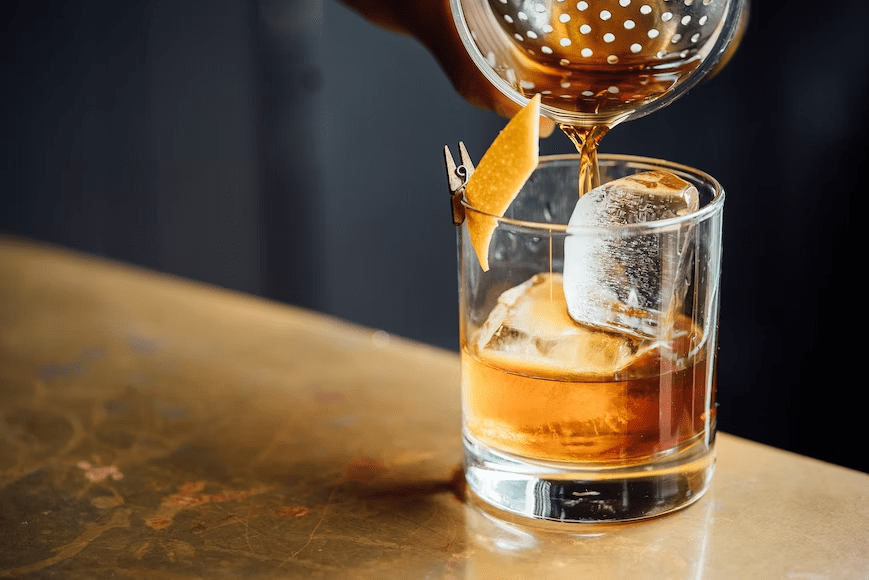 whiskey being poured into a small glass with ice.