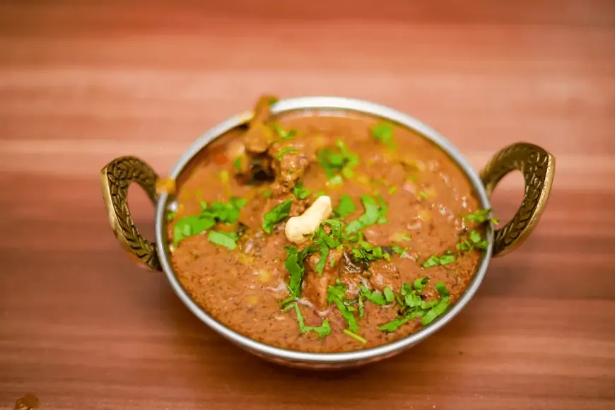 a stylish metal bowl with handles containing a curry
