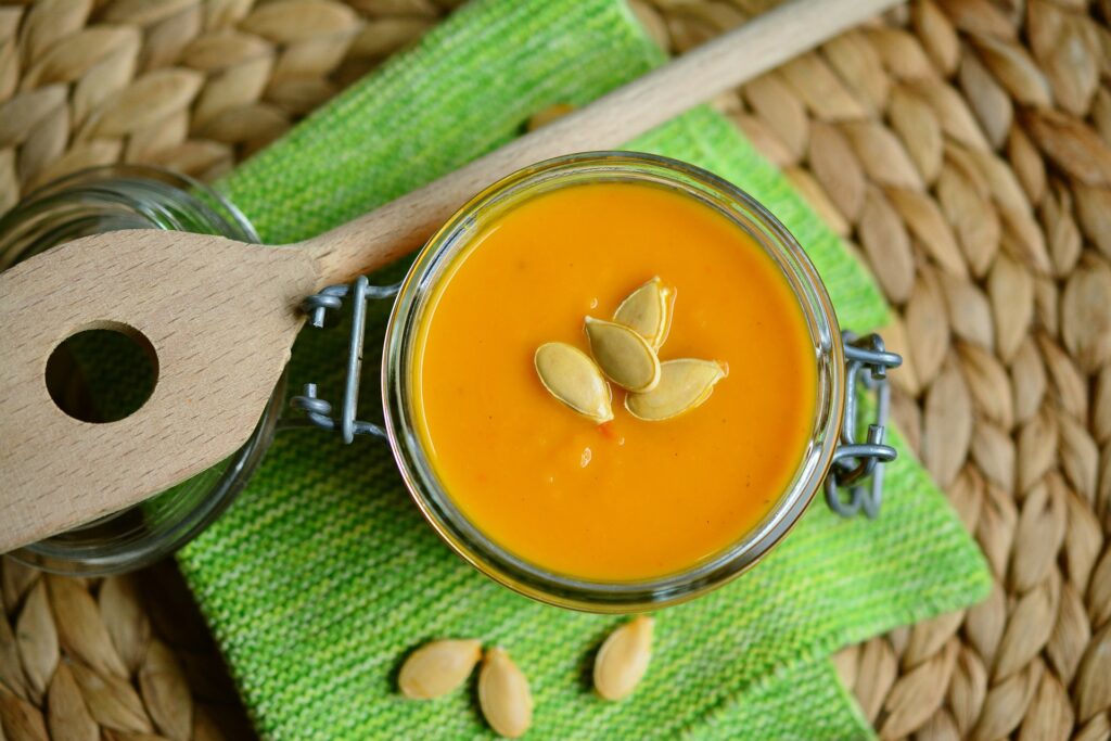 Pumpkin Soup in a Mason Jar, with a wooden spoon resting on a green cloth