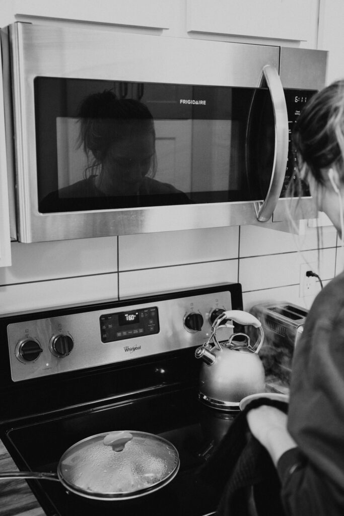 woman standing in front of her whirlpool stove top with a microwave on the wall above