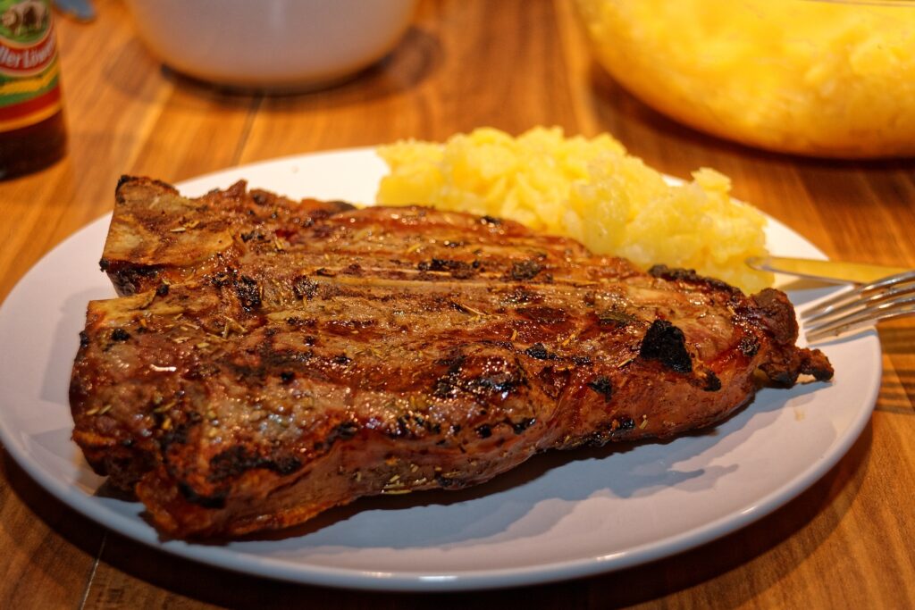 air fried T-Bone steak on a white plate with mash on the side