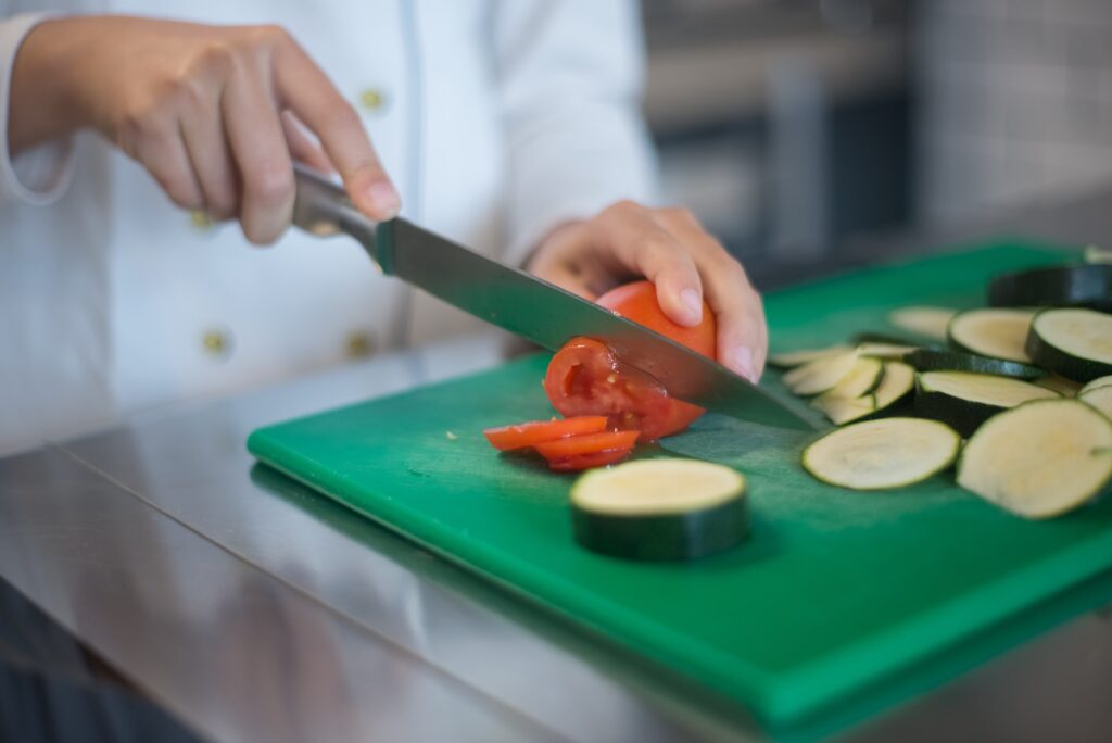chef chopping capisucm  and zucchinbi on a green chopping board