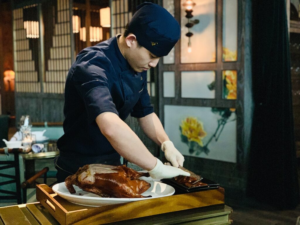 Asian chef slicing a roasted duck