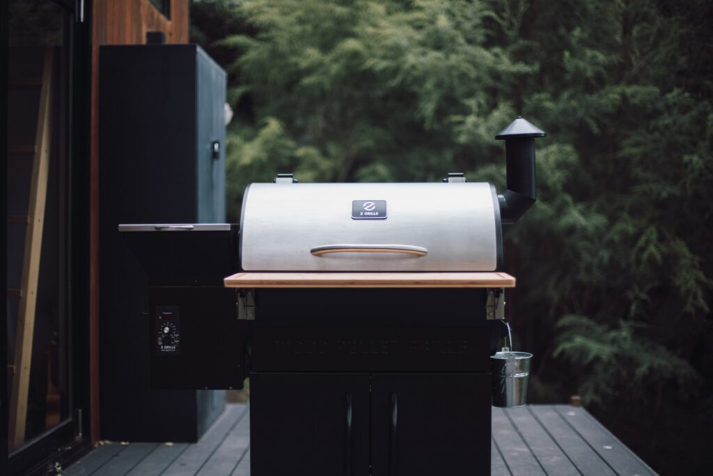 a bbq with the lid down on a timber deck with black cupboards behind