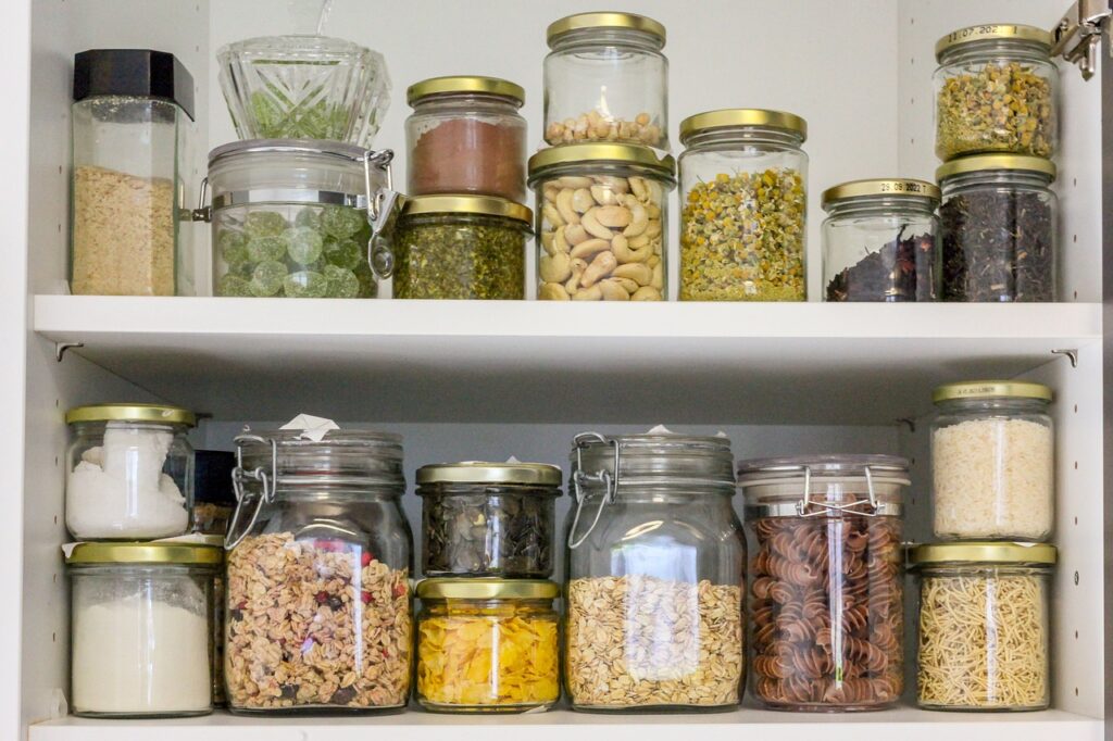 glass jars on the pantry shelf filled with common cooking ingredients from pasta to spices