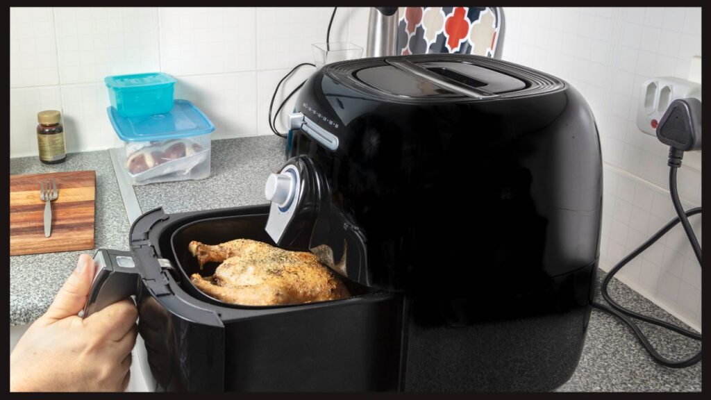 black air fryer with a large basket containing an air-fried chicken