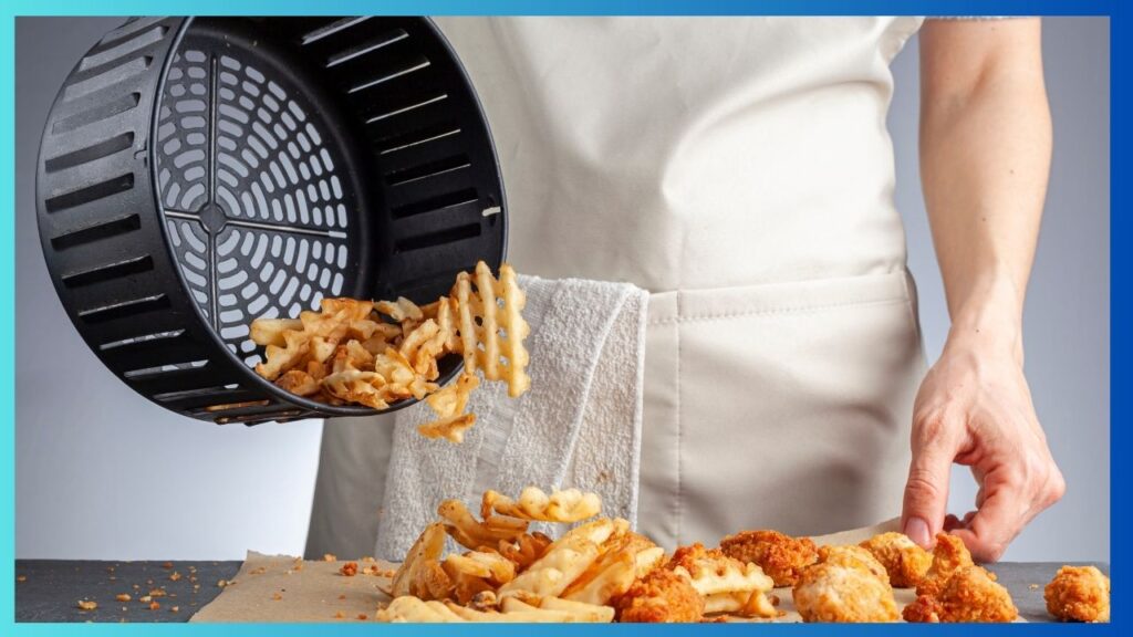 kitchen cook pouring fried chips from an air fryer basket onto a grease proof paper lined kitchen bench