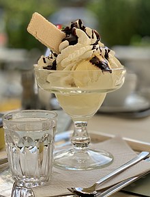 Ice cream in a glass bowl with whipped cream, chocolate syrup and a wafer